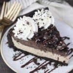 An overhead view of a mudslide pie covered with Oreos, chocolate drizzle and whipped cream