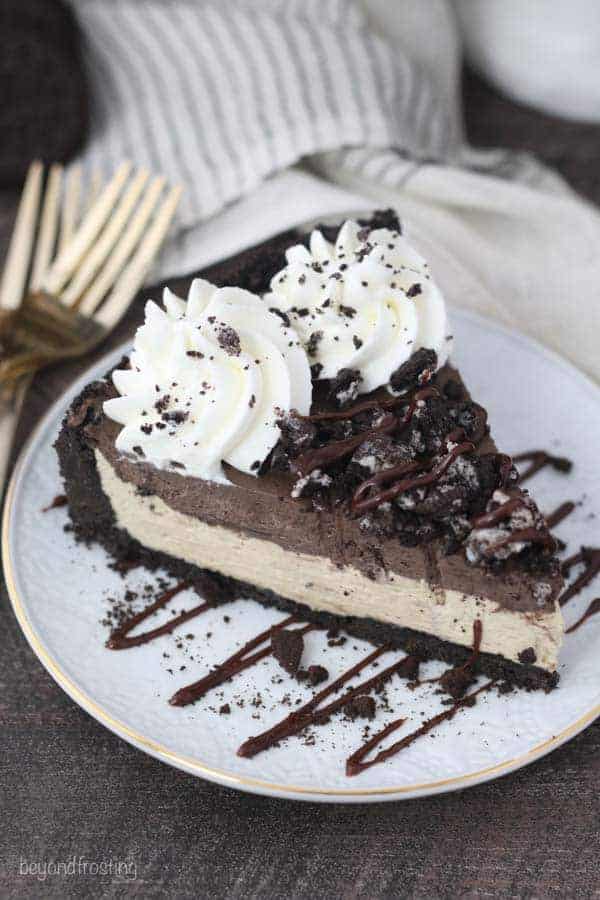 An overhead view of a mudslide pie covered with Oreos, chocolate drizzle and whipped cream