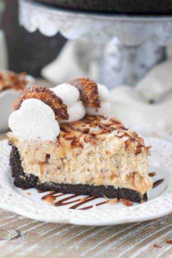 An overhead shot of a no-bake caramel coconut Samoa cheesecake. Topped with whipped cream, samoa cookies, caramel and hot fudge sauce