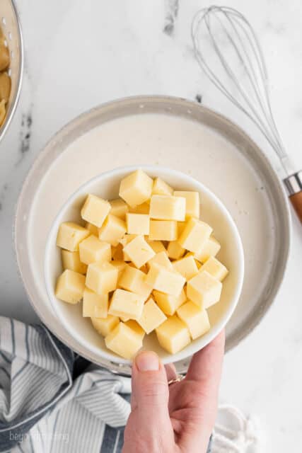 Cubes of white cheddar cheese in a bowl over a pan