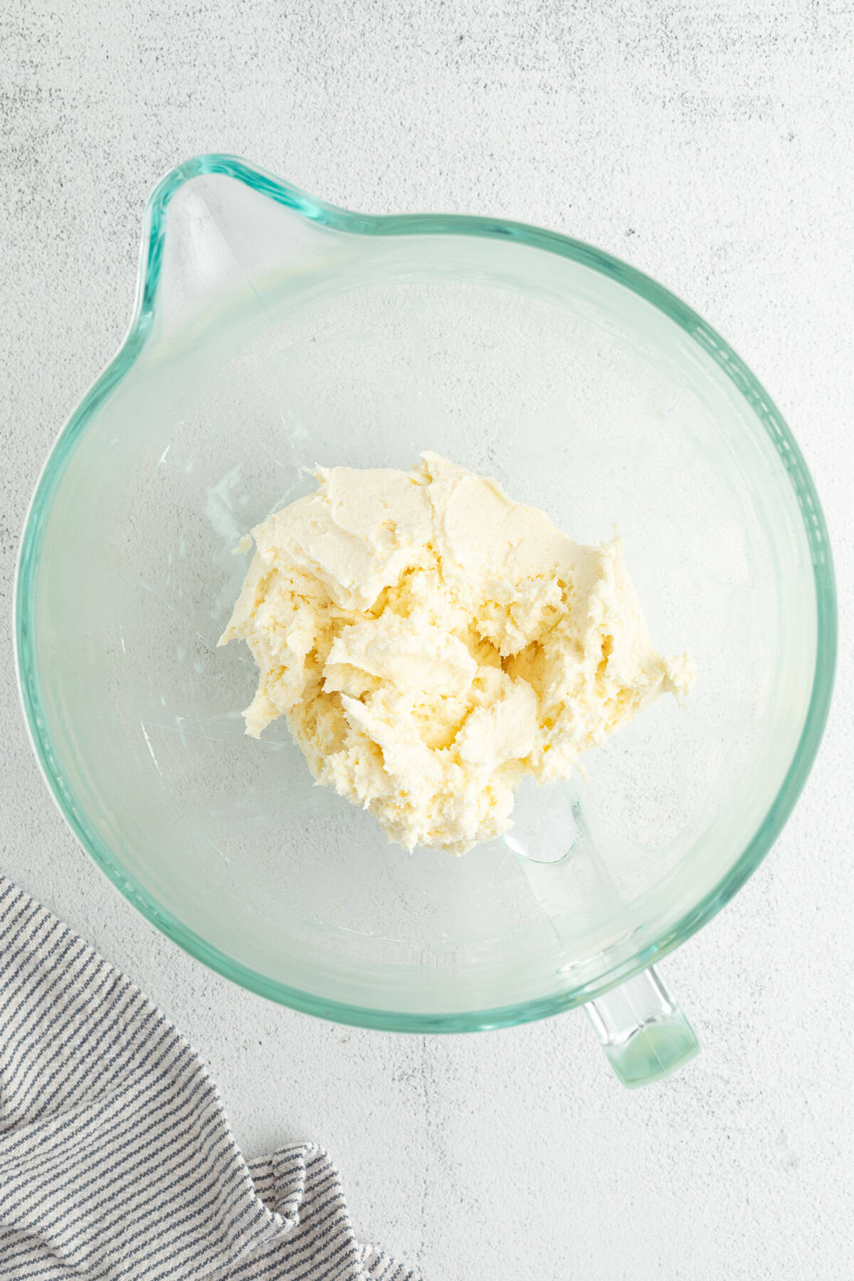 This blueberry bundt cake is a moist pound cake recipe with added almond flavor and juicy blueberries, topped with tangy cream cheese icing. Cream cheese and butter mixed in a bowl.