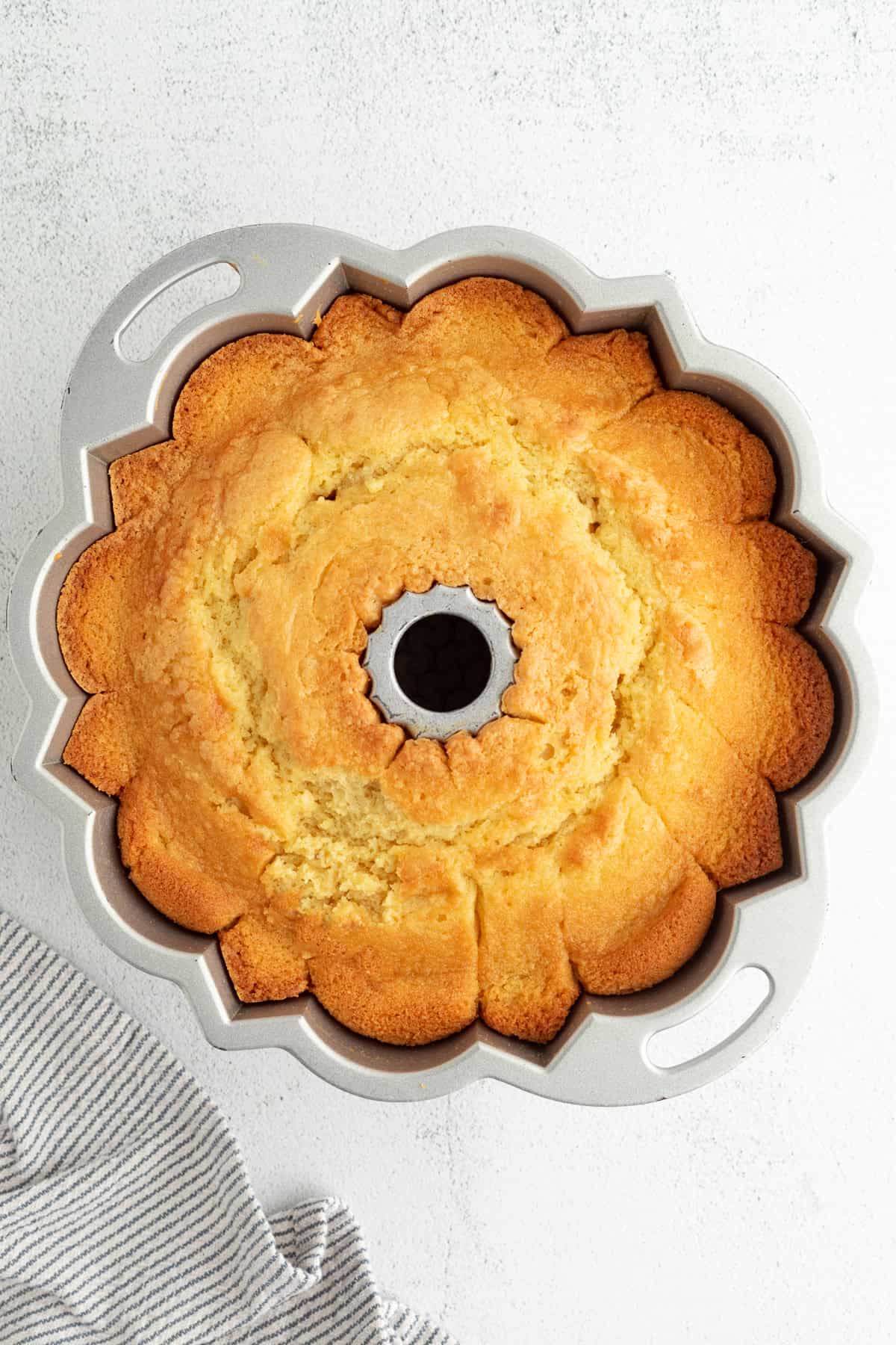 This blueberry bundt cake is a moist pound cake recipe with added almond flavor and juicy blueberries, topped with tangy cream cheese icing. Baked blueberry almond bundt cake in a bundt pan.