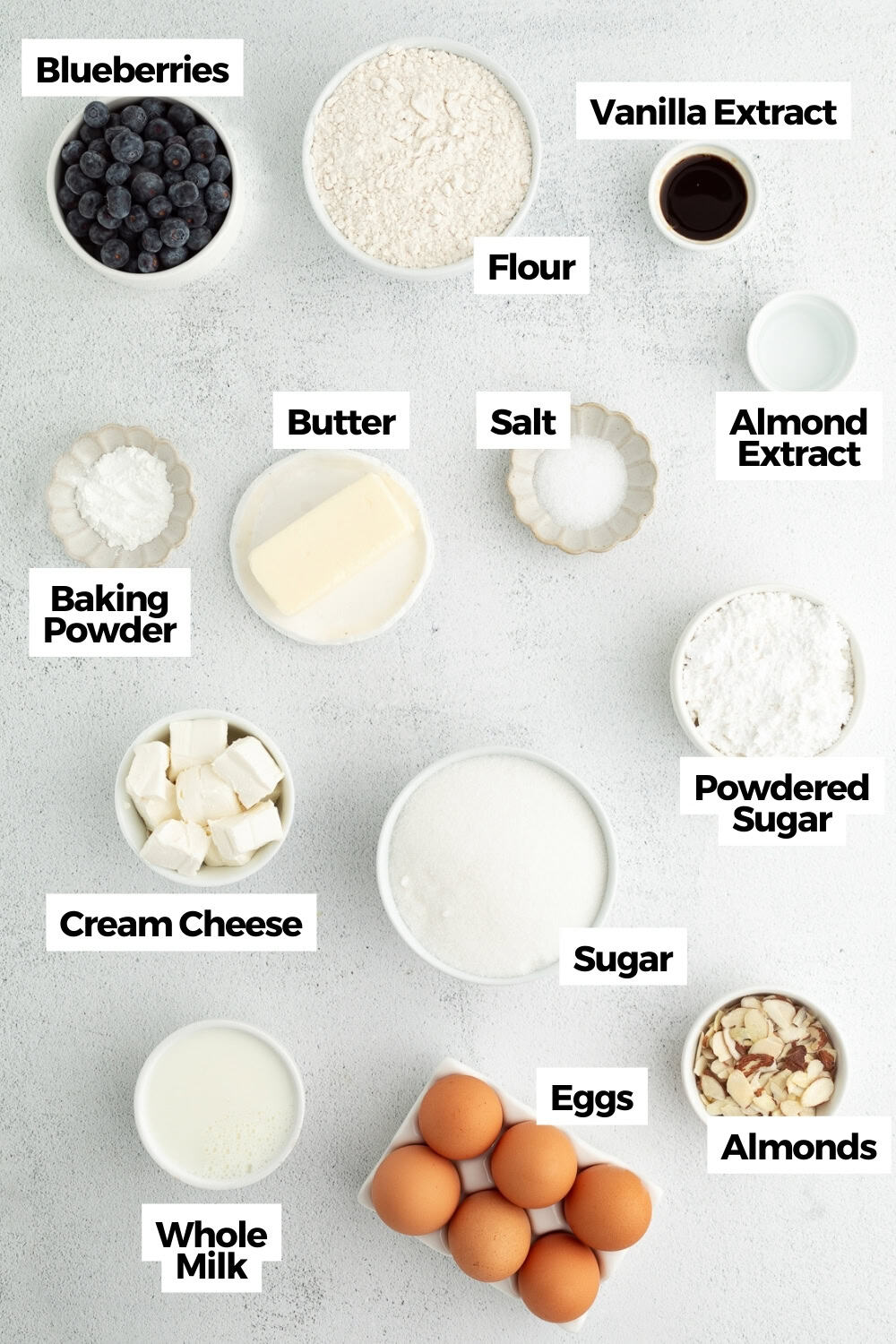 This blueberry bundt cake is a moist pound cake recipe with added almond flavor and juicy blueberries, topped with tangy cream cheese icing. Blueberry almond bundt cake ingredients with text labels overlaying each ingredient.