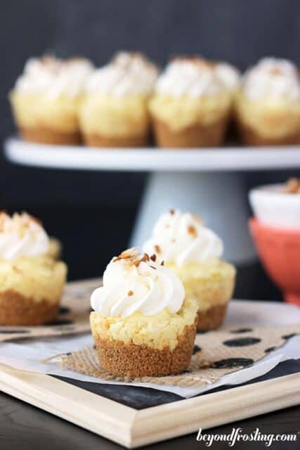 Cookie cups on a white cake plate with a graham cracker crust, a coconut filling and whipped cream