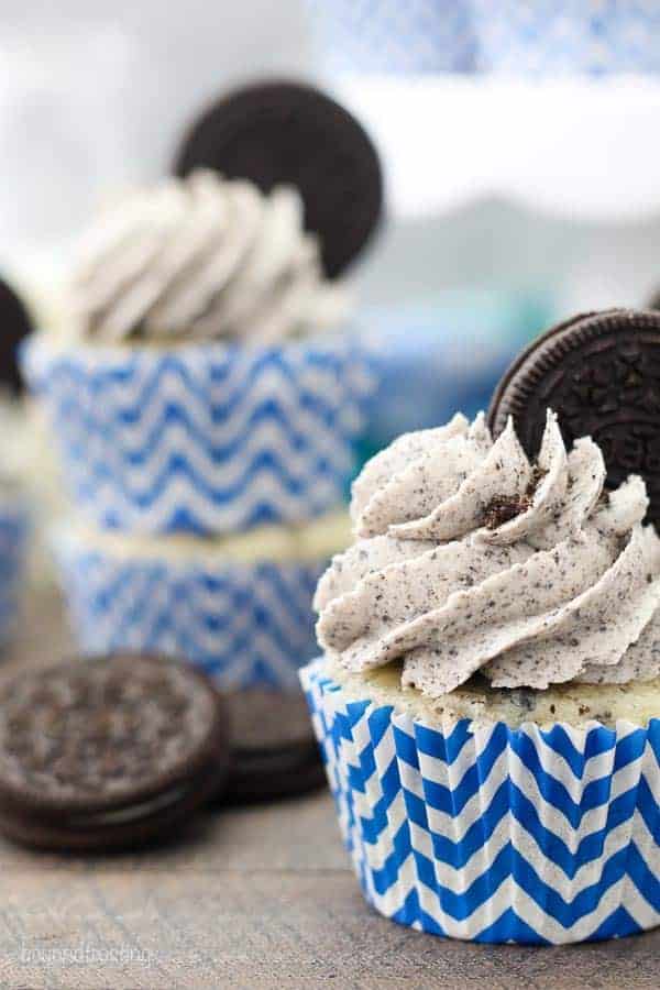 A close up photos of a cookies and cream cupcake with an Oreo buttercream that has an Oreo stuck into the frosting