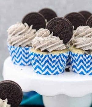 A few Cookie and Cream Oreo Cupcakes sitting on a white cake plate