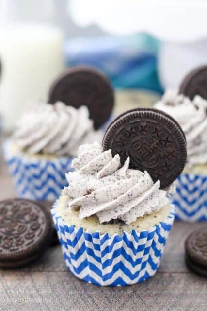 A close up photos of a cookies and cream cupcake with an Oreo buttercream that has an Oreo stuck into the frosting