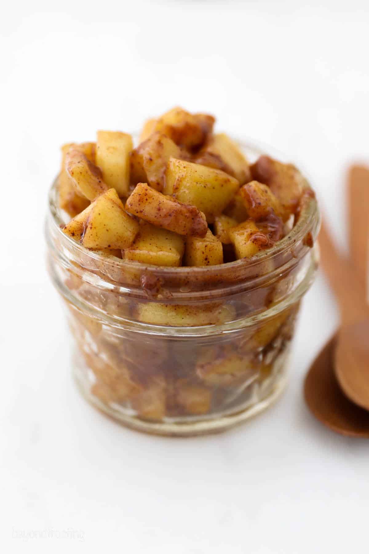 A jar of apple pie filling next to a spoon.
