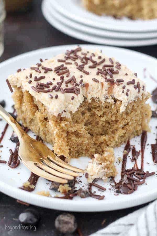  Une tranche de gâteau au moka sur une assiette blanche recouverte d'un glaçage au café Kahlua et de pépites de chocolat. Cette tranche de gâteau contient quelques bouchées.