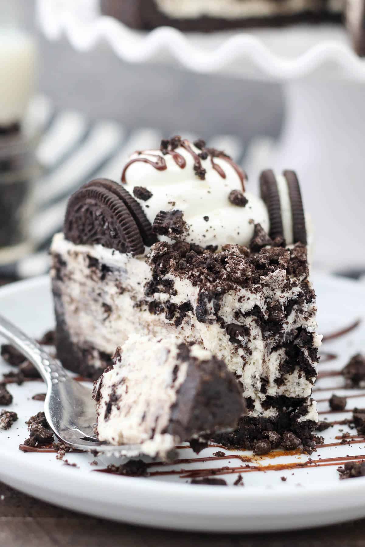 A slice of no-bake cheesecake loaded with Oreos with a big forkful taken off the tip.