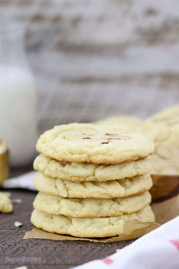 A stack of 5 almond cookies on brown parchment paper.