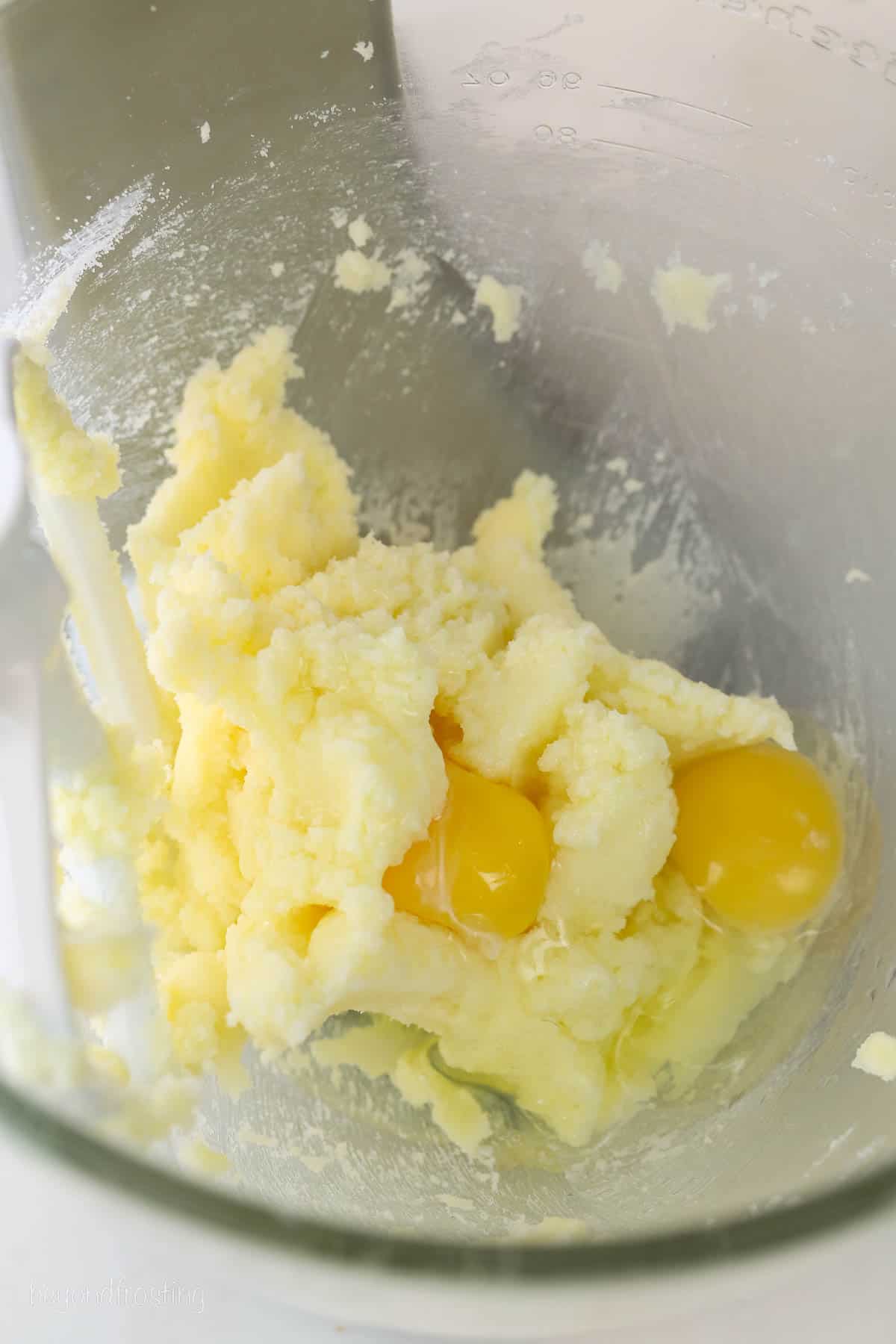 Eggs added to creamed butter and sugar inside the bowl of a stand mixer.