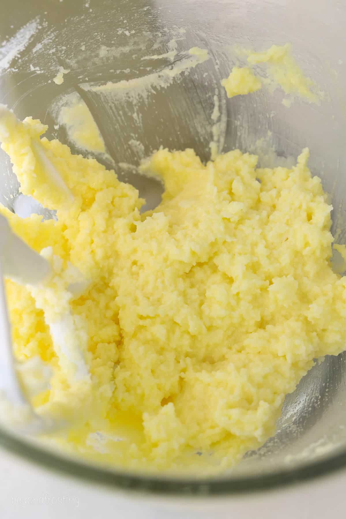Wet ingredients for almond cookie dough are creamed together in the bowl of a stand mixer.