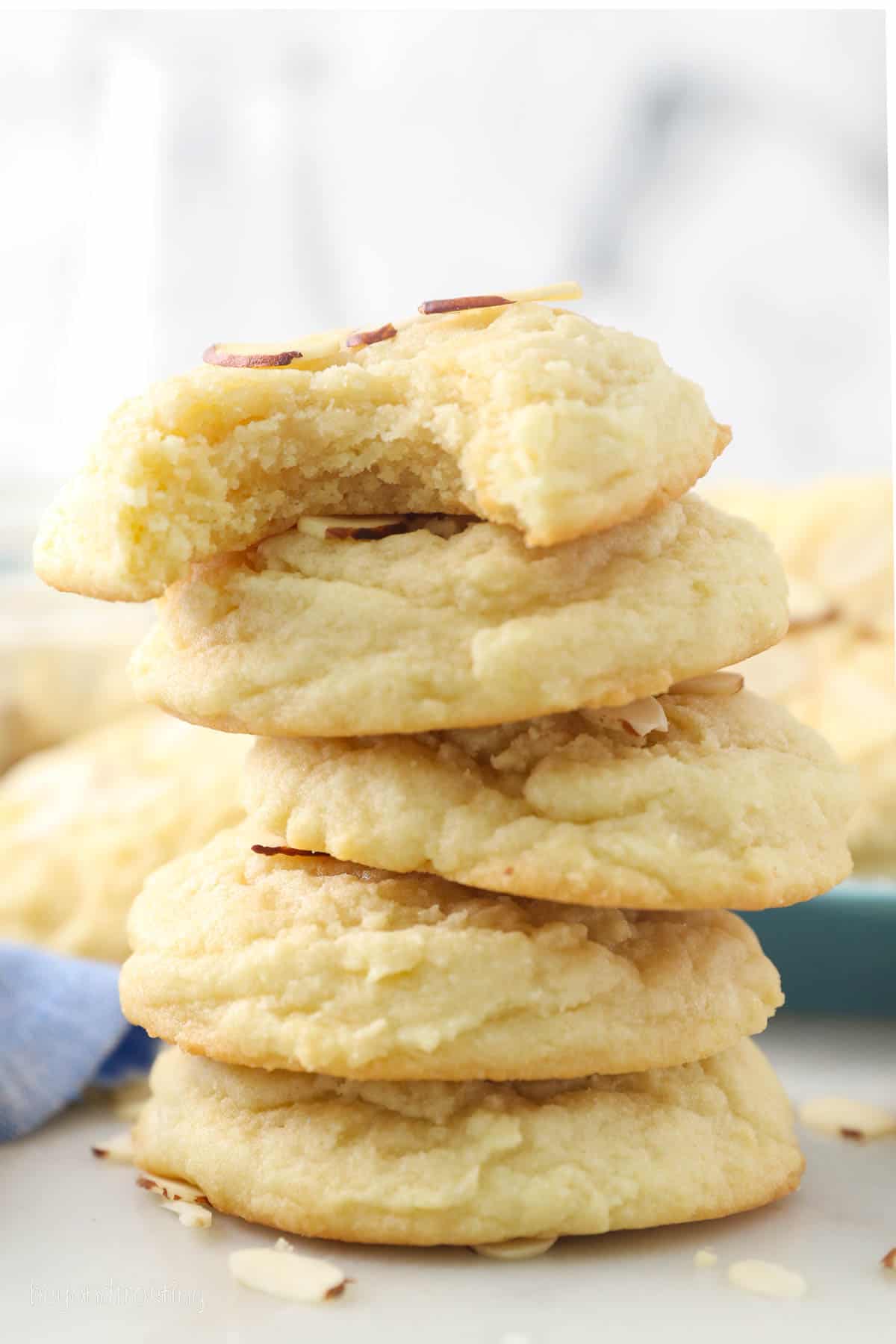 A stack of almond cookies with a bite missing from the top cookie.