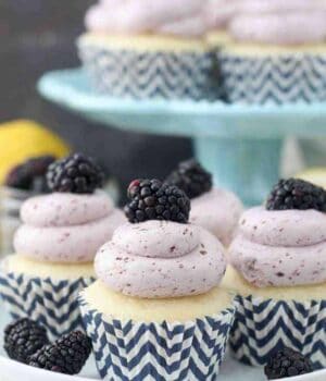 A plate of cupcakes with blue chevon cupcake liners, topped with a light purple colored, blackberry Swiss meringue buttercream