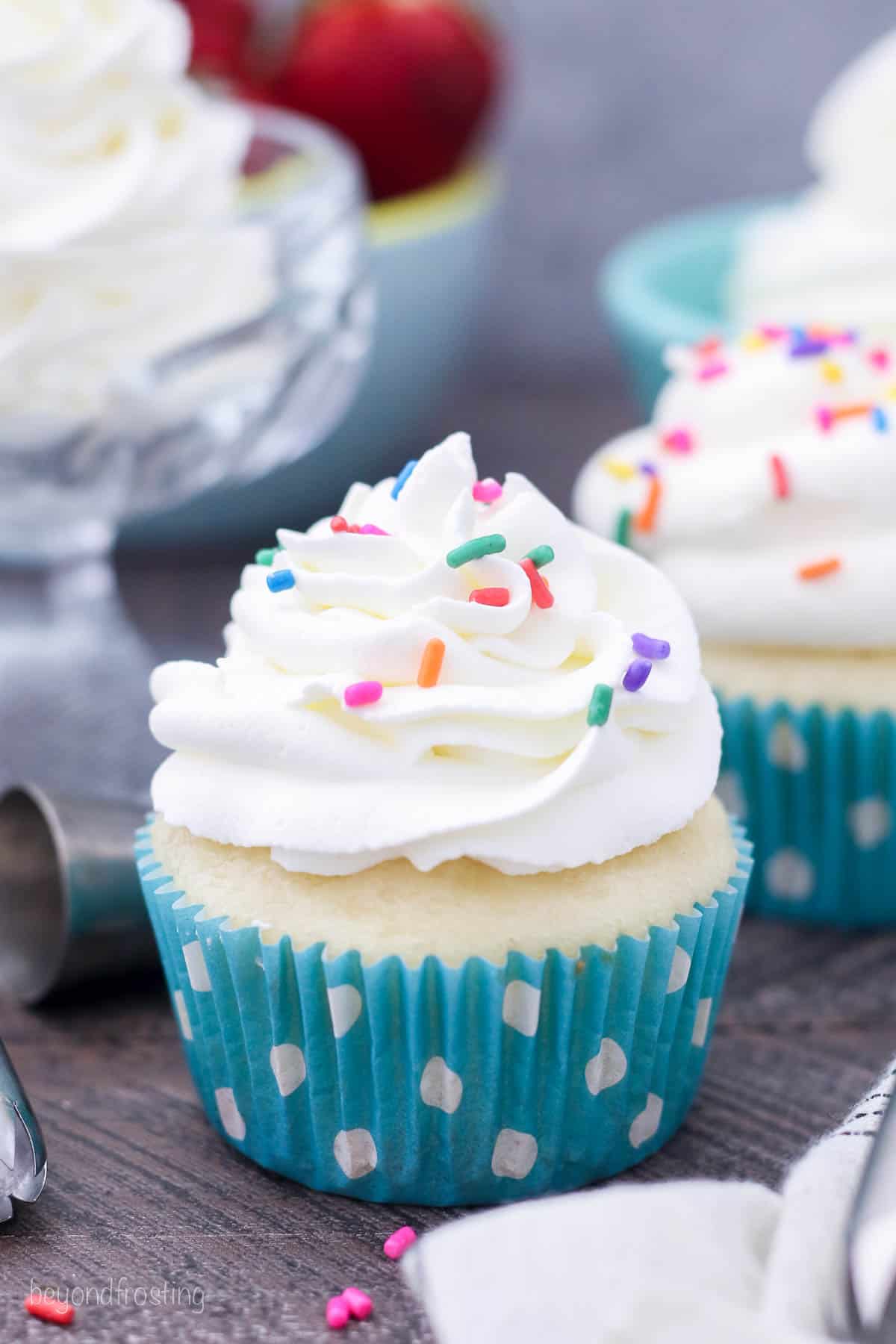A cupcake topped with piped whipped cream and colored sprinkles.