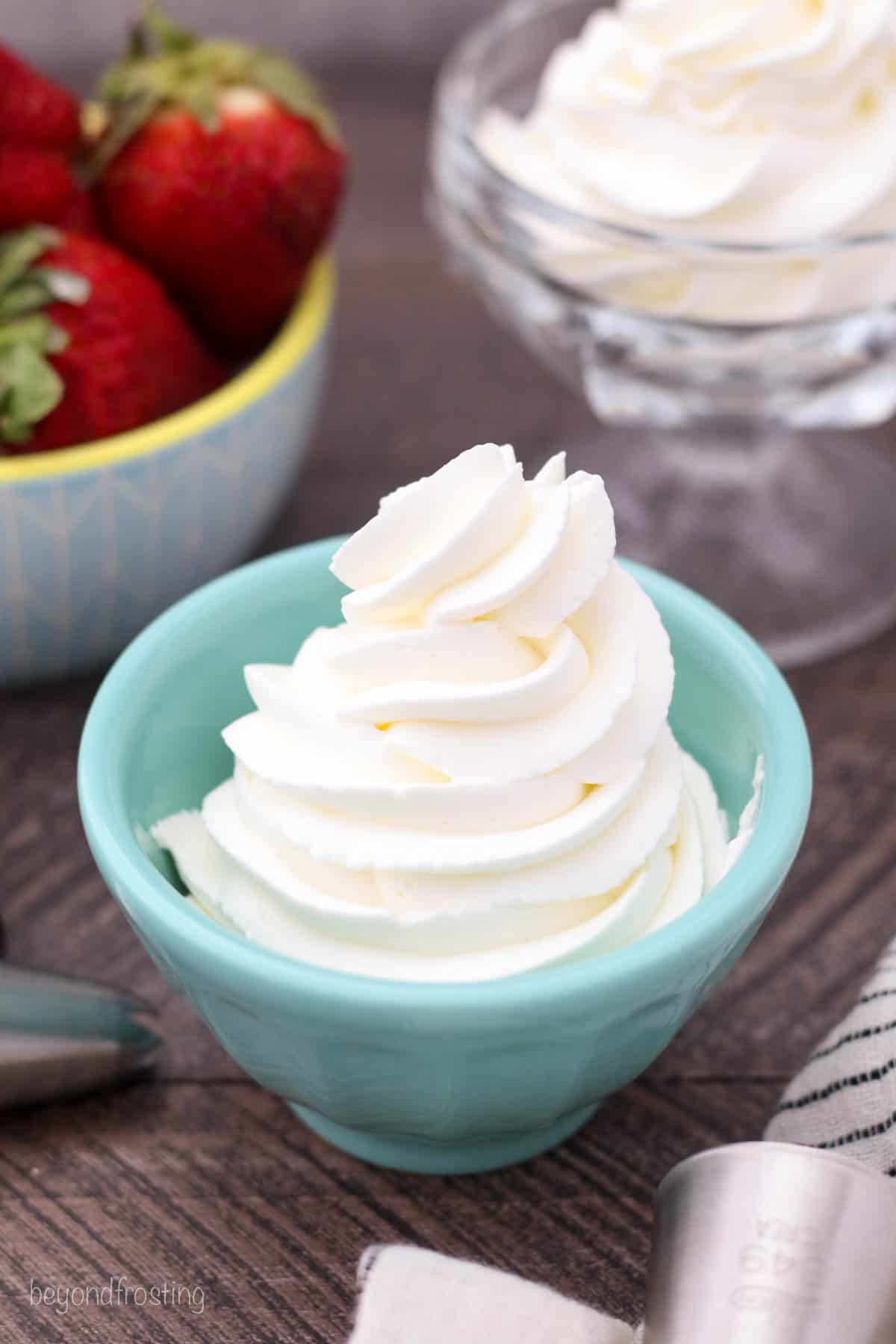 Overhead view of a swirl of whipped cream piped into a teal bowl.