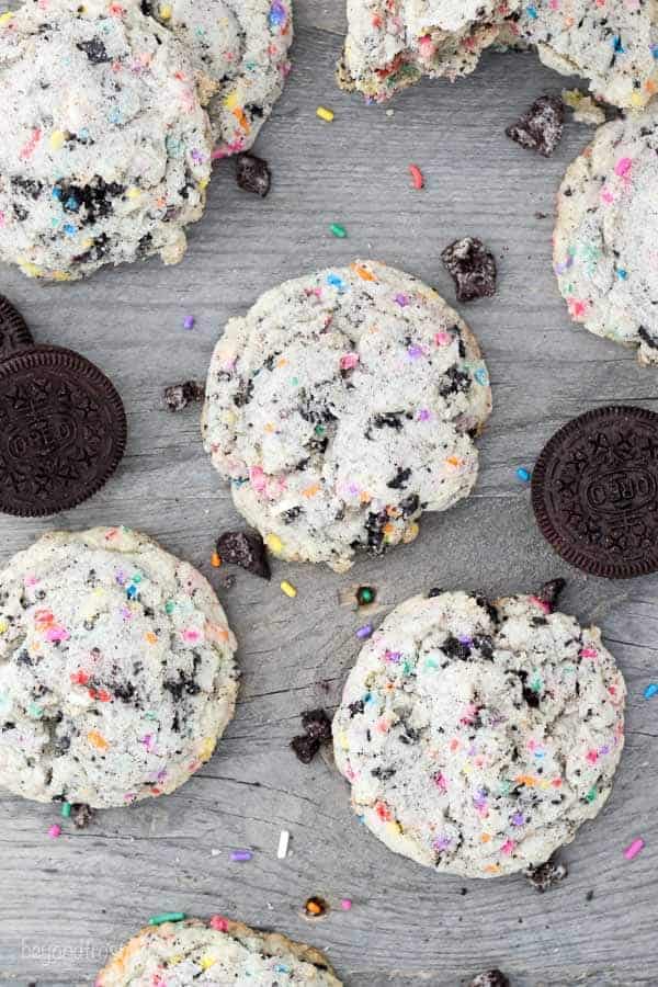 Cookies laid out on a wooden surface. The cookies are stuffed with Oreos and sprinkles.