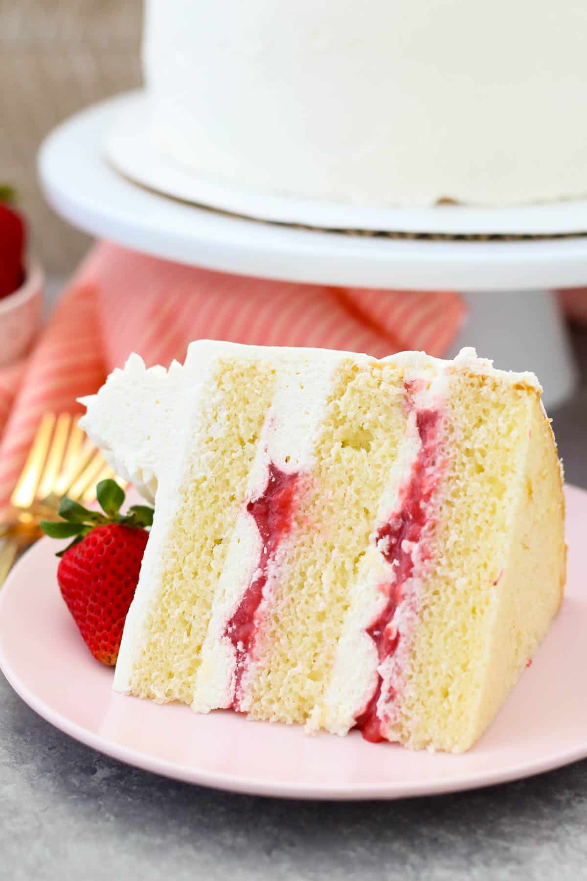 A slice of strawberry mascarpone cake on a pink plate.