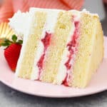 A slice of strawberry mascarpone cake on a pink plate.