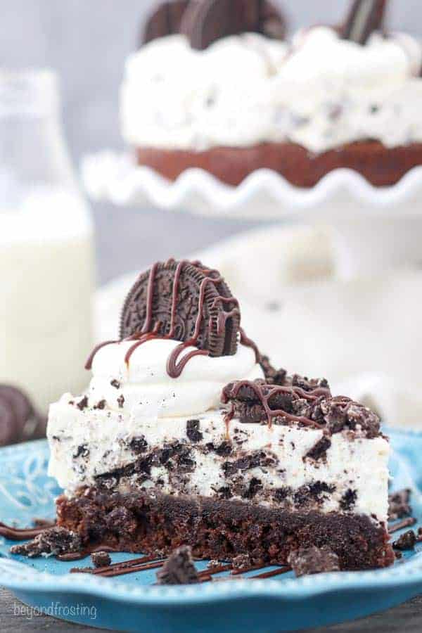 A close up shot of an Oreo Brownie Pie topped with whipped cream and crushed Oreos on a blue plate