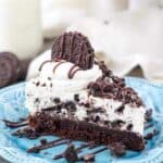 A slice of Brownie Oreo Mousse Pie on a teal plate sprinkled with crushed Oreos