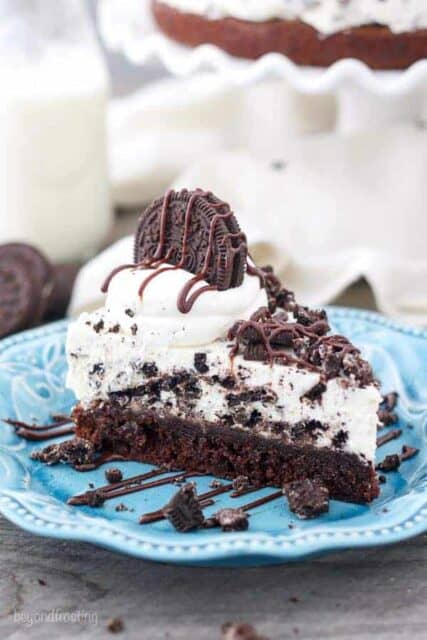A slice of Brownie Oreo Mousse Pie on a teal plate sprinkled with crushed Oreos