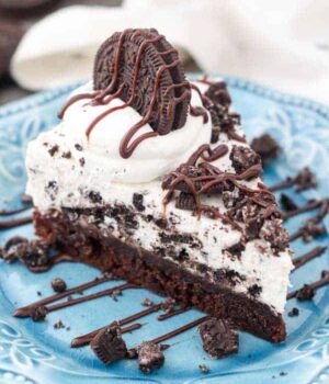 An overhead view of a slice of Oreo pie with a layer of brownie on the bottom, and garnished with more Oreos and hot fudge