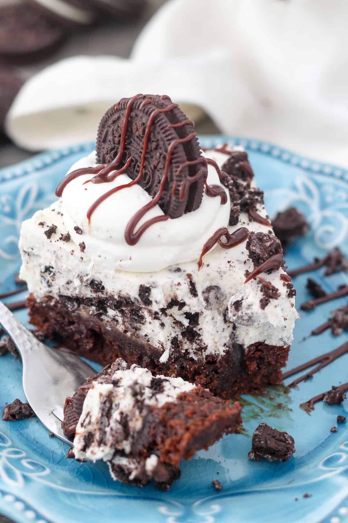 This Oreo mousse pie layers a fudgy brownie with silky white chocolate mousse and lots of crushed Oreos! It's a fun & easy make-ahead dessert. A forkful missing from the end of a slice of Oreo mousse pie on a plate.