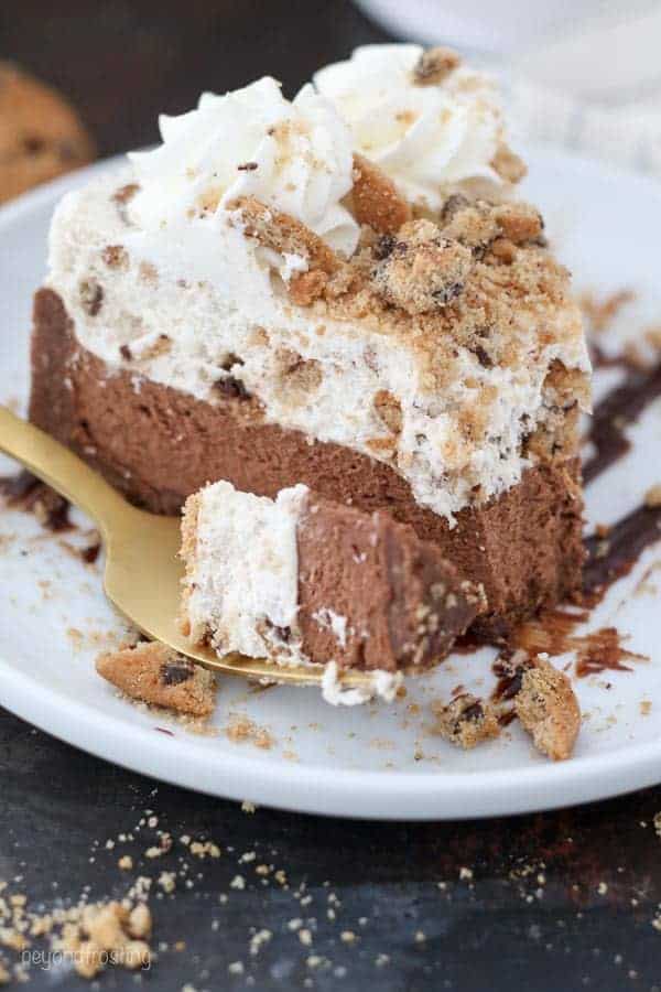 A close up of a chocolate mousse cake with a layer of chocolate chip cookie mousse on top with a giant bite taken out of it.