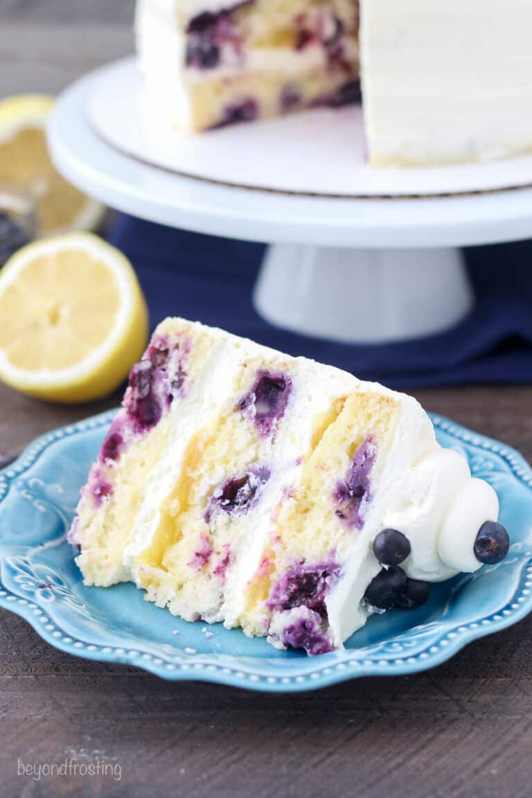 Slice of lemon blueberry layer cake on a blue plate.