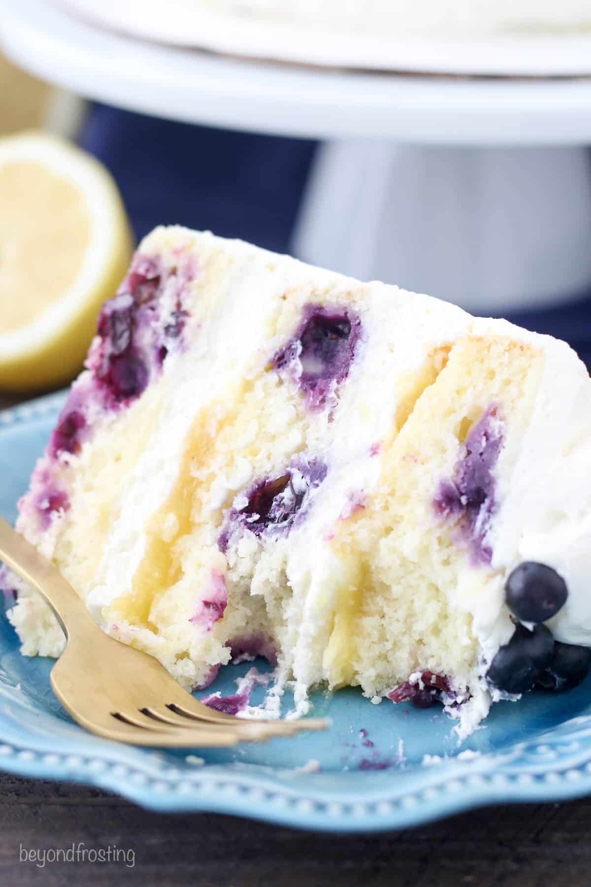 A slice of lemon blueberry cake with a bite taken out