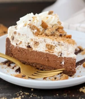 A slice of chocolate chip cookie mousse cake on a plate next to a fork.