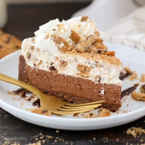 A slice of chocolate chip cookie mousse cake on a plate next to a fork.