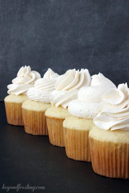 A line of cupcakes all frosted with different types of frosting techniques