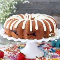 A large strawberry bundt cake on a white cake plate with a scallop edge