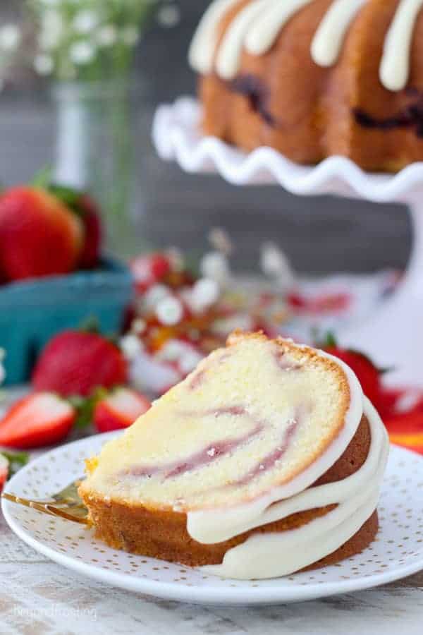 A slice of pound cake with a cream cheese glaze laying on a gold polka dot plate..