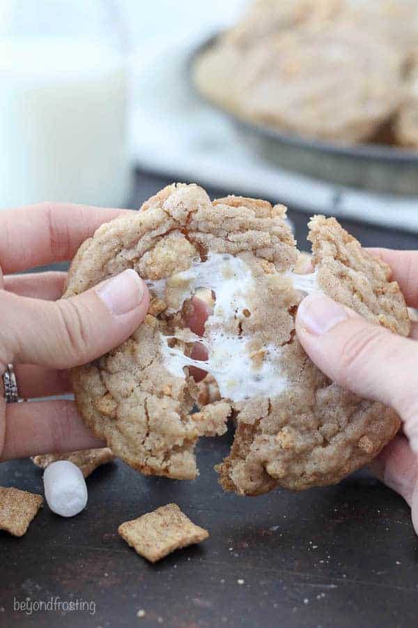 Two hands pulling apart a gooey marshmallow cookie.