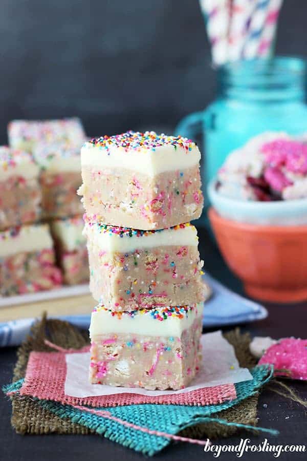 Cookie Dough Truffle Bars are stacked on top of one another, lot of sprinkles and white chocolate on top