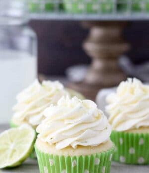 A group of 3 cupcakes with green polka dot wrapper stacked together with a lime wedge in the background
