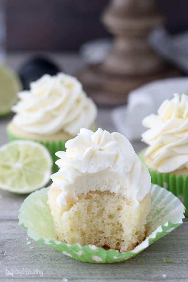 A shot of a tequila spiked cupcake with lime frosting and a giant bite taken out of it