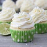 A horizontal images of a group of cupcakes with a sliced lime and green polka dot cupcake liners