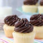 Three yellow cupcakes stacked together. These cupcakes are topped with chocolate frosting and sprinkles.