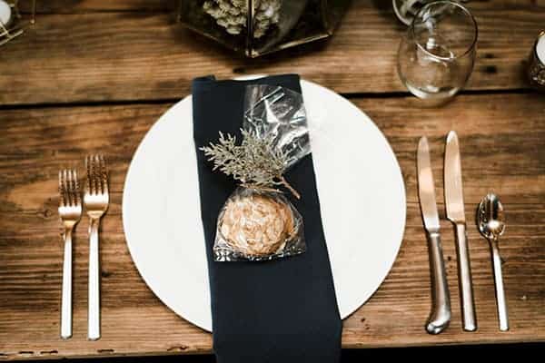 A navy blue napkin with homemade cookie favors and a juniper branch © Kimberly Kay Photography
