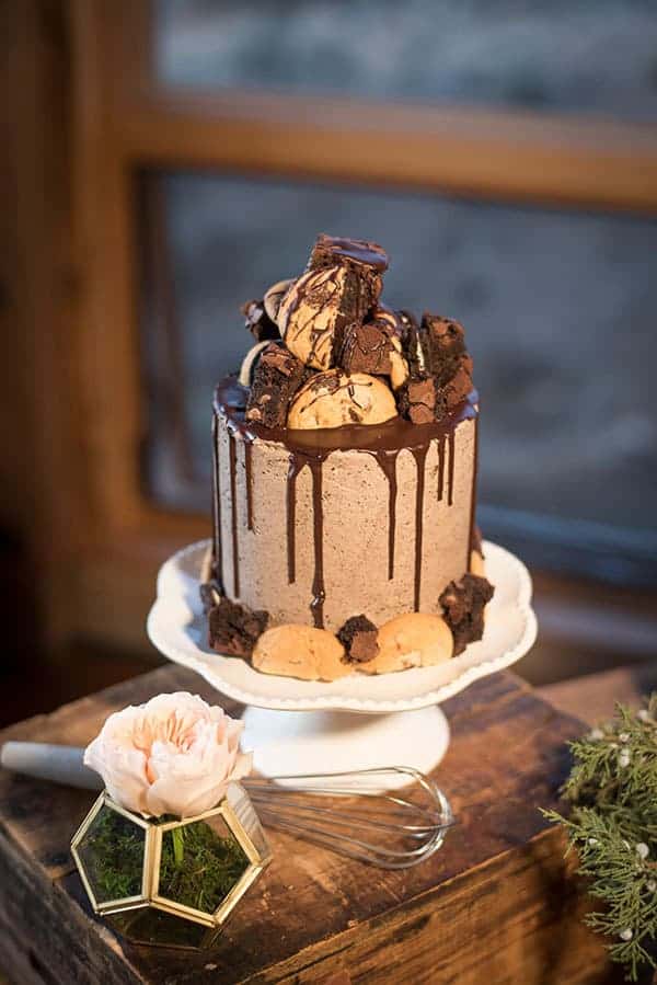 A tall cake with Oreo frosting covered in cookies, brownies and Oreos