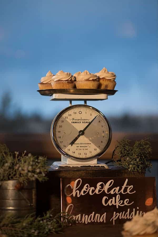 A vintage scale with a rustic metal plate and cupcakes on top were the centerpiece for this rustic dessert table