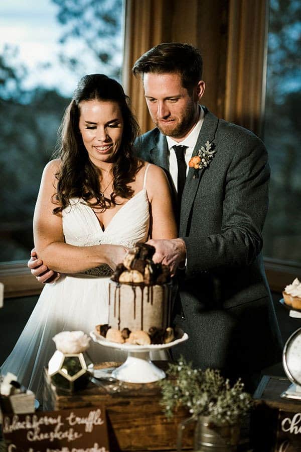 Bride and Groom cut into a Brookie Cake for their rustic bar wedding © Kimberly Kay Photography