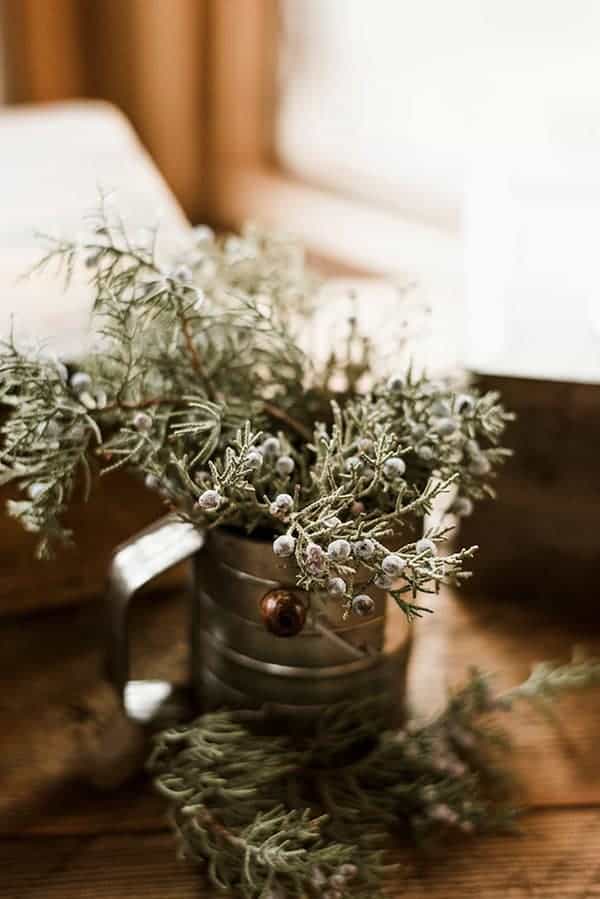 A rustic flour sifter filled with Juniper branches for a dessert table