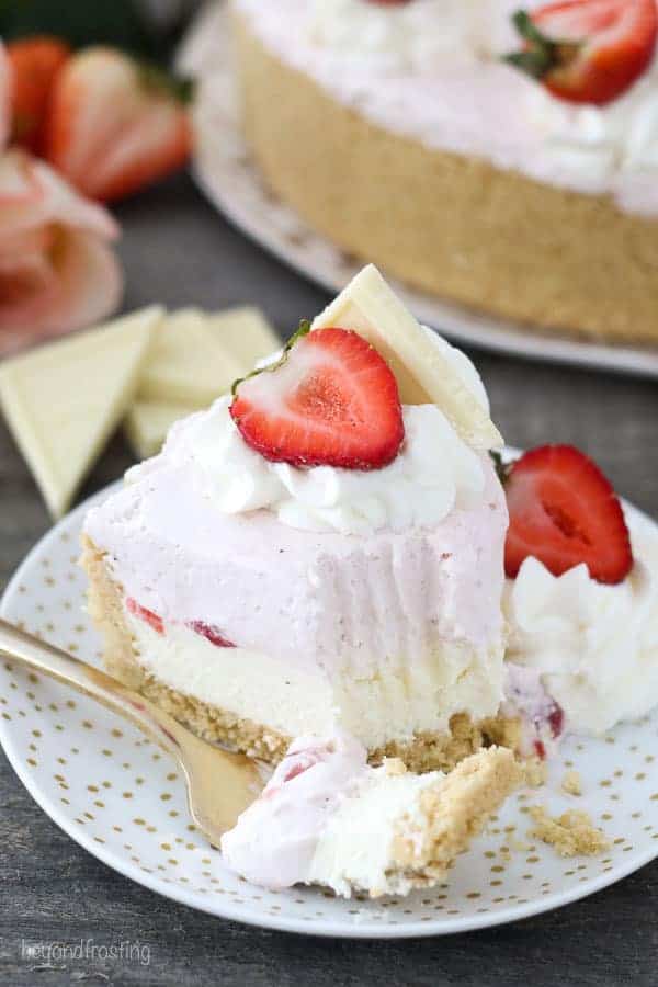 A slice of strawberry mousse cake with a few bites taken out of it.