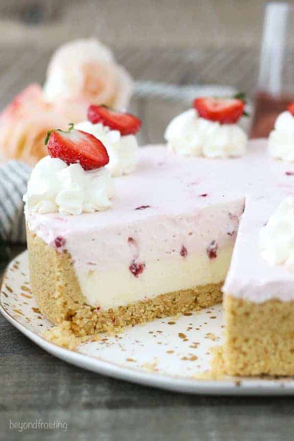 A large strawberry mousse cake with a slice taken out of it